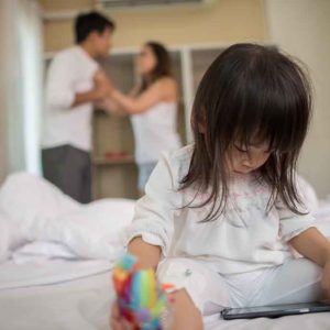Little Girl sitting with her parents on the bed looking serious Little Girl sitting with her parents on the bed looking serious